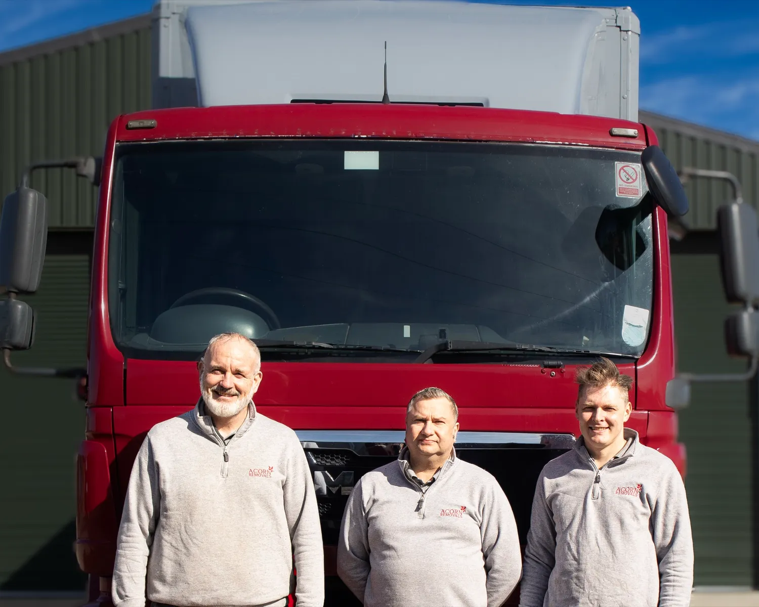Three Acorn team members alongside an Acorn Removals lorry at the Newbury depot